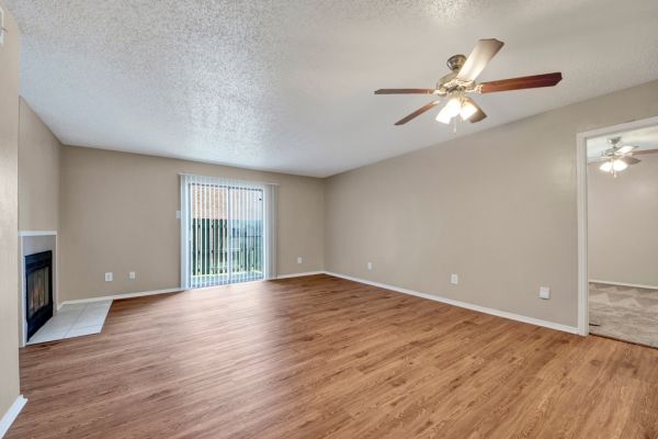 Spacious living room with wooden floor, and sliding glass door leading to a balcony.